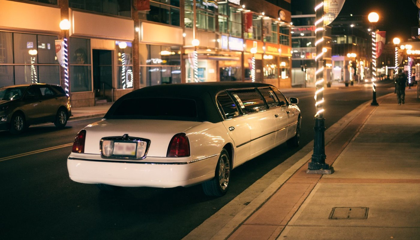 White stretch limousine parked on a city street at night, ready for prom night transportation