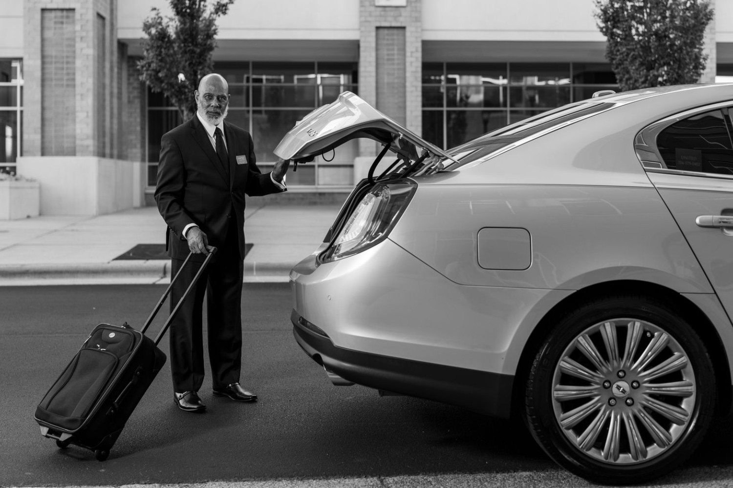 Chauffeur loading luggage into a black car for an airport transfer
