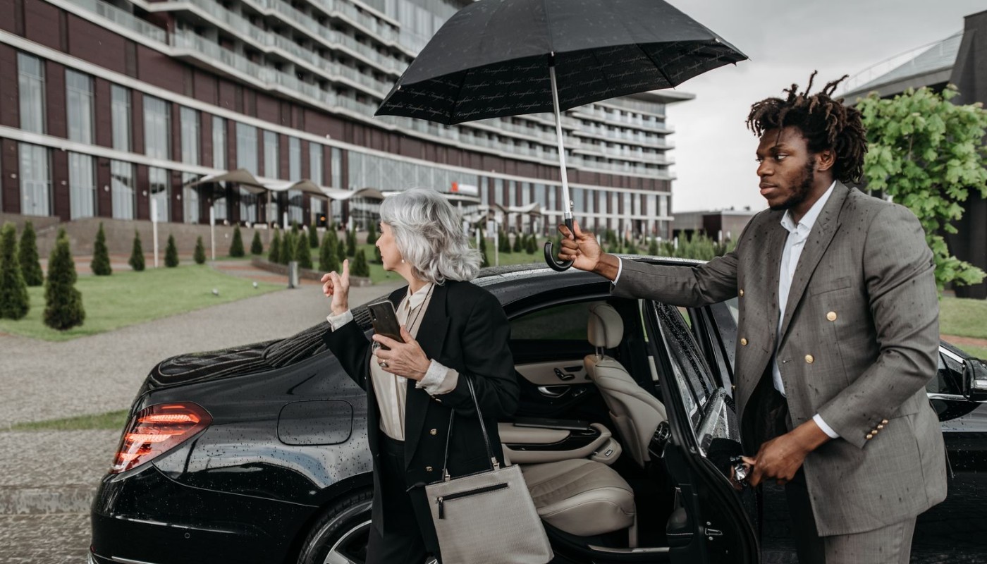Executives exiting a luxury car with a chauffeur assisting
