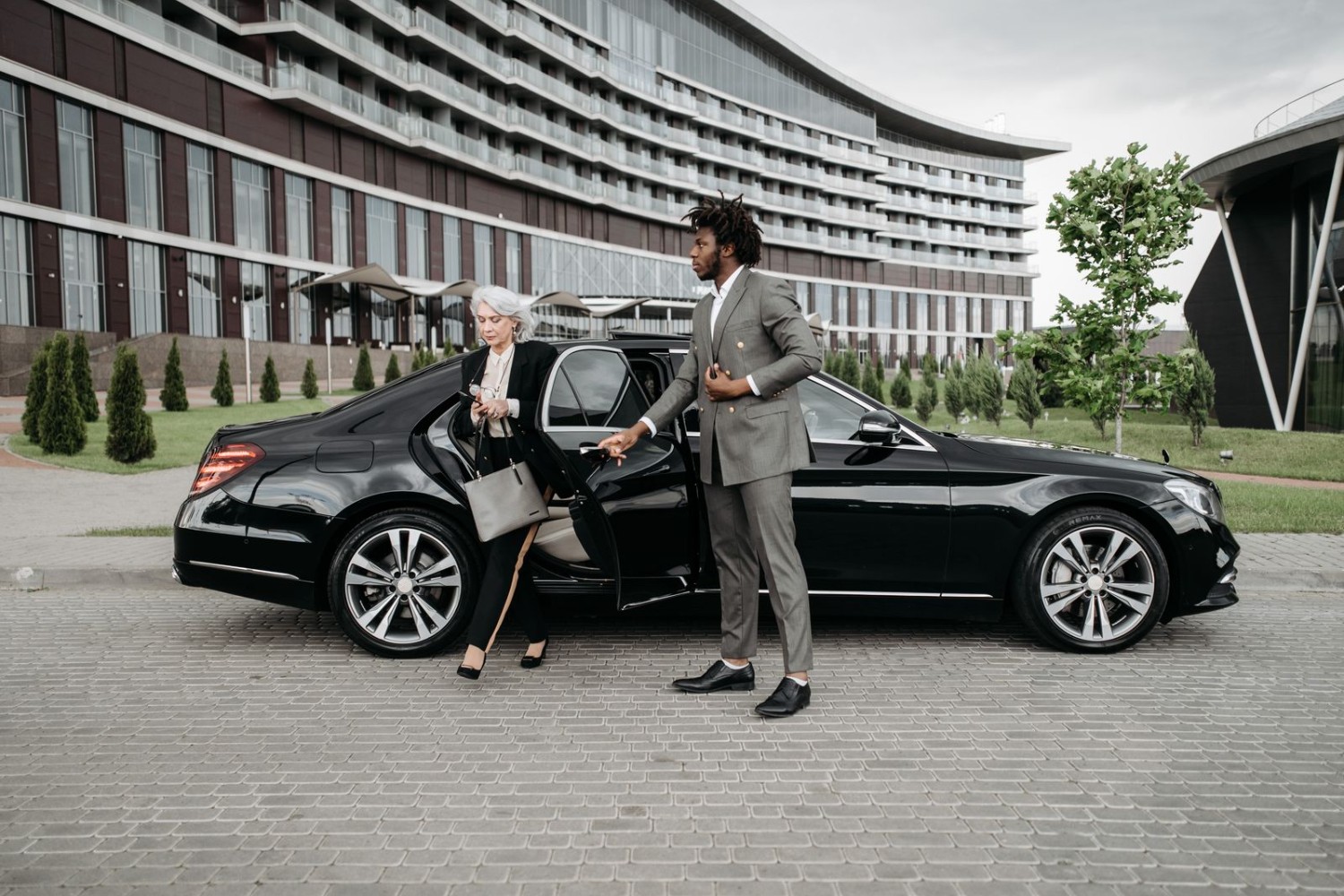 Chauffeur assisting a business executive out of a luxury car