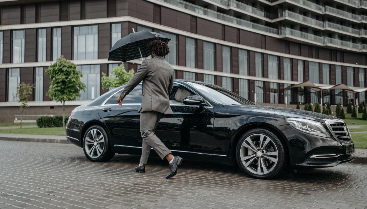 Chauffeur opening a black car door for an executive