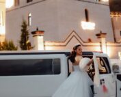 Bride beside a limousine outside an illuminated venue at twilight